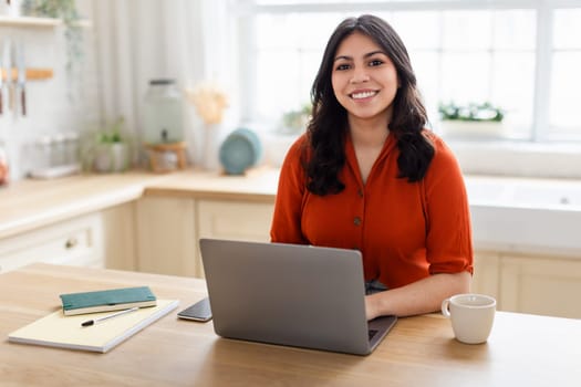 Happy woman working on laptop in kitchen