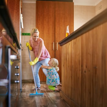 Mother, girl and cling on leg to sweep floor for cleaning, care and broom for dirt or dust in home. Mommy, daughter and loving child for hygiene or housework, maid and tidy apartment for service.