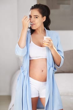 Pregnancy, portrait and girl in home with yogurt for snack, craving and nutrition in bedroom. Pregnant woman, abdomen and dessert or ice cream for vitamin, protein and wellness for belly or stomach.