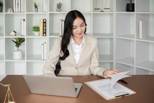 A female Asian lawyer reviews business and real estate laws. Legal consultants provide legal advice and guidance online via laptops in lawyers' offices.