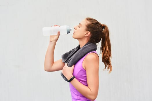 Woman, athlete and drinking water in studio, relax and hydration after workout on white background. Female person, profile and mineral liquid for recovery after exercise, fitness and mockup space