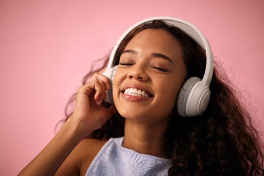 Happy girl, relax and listening to music with headphones for jazz or beats on a pink studio background. Female person enjoying podcast, audio streaming or sound with smile for radio, song or playlist