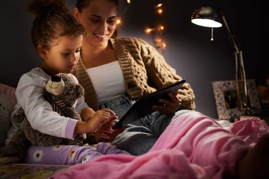 Mother, girl kid and tablet in bed, comfort and storytelling for bed time routine, bonding and love at family home. Woman, daughter and together in bedroom at night with ebook, safety and security.