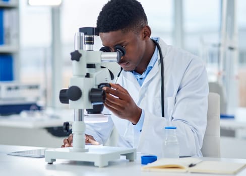 Science, notes and black man with microscope for research, investigation or medical engineering in laboratory. Biotech, lab technician or scientist checking vaccine sample for pharmaceutical test.