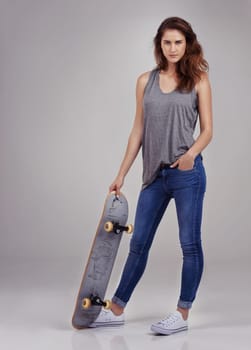 Portrait, skateboard and woman in gray background for fashion with health, sports and workout. Long board, isolated and gen z model by studio with transport for exercise, clothes and sustainability