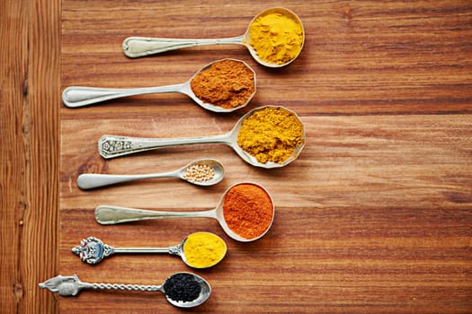 Colour, curry and spices on vintage spoon with natural ingredients to cook dinner. Asian, power and seasonings for hot, spicy and delicious authentic Indian food with flavour on tabletop in kitchen
