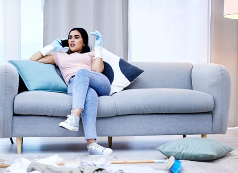 Woman, phone call and cleaning on sofa and gossip, communication and relax on couch of house. Smartphone, housewife and talking for virtual conversation, dirty and messy home living room and chores.