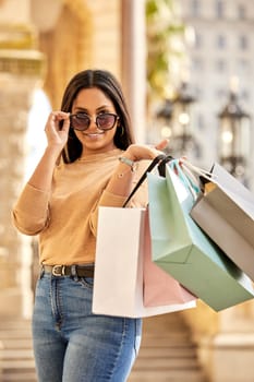 Portrait, shopping bag and woman in city happy on urban street for boutique, retail and clothing sale. Female person, sunglasses and smile outdoors with luxury products for fashionable rich customer