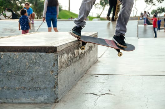 Skateboarder is doing a crooked grind trick on a bench in skatepark.