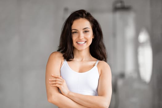 Confident woman posing with arms crossed in bathroom