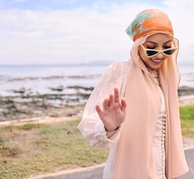 Fashion, sea and happy Muslim woman in nature with style, trendy clothes and casual outfit in Saudi Arabia. Religion, hijab and Islamic person with confidence, pride and sunglasses on summer weekend