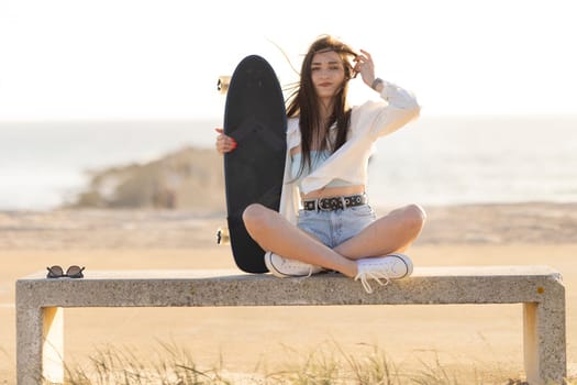 A woman is sitting on a bench with a skateboard in her hand