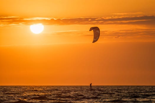 Kiteboarding kitesurfing kiteboarder kitesurfer kites silhouette in the ocean on sunset