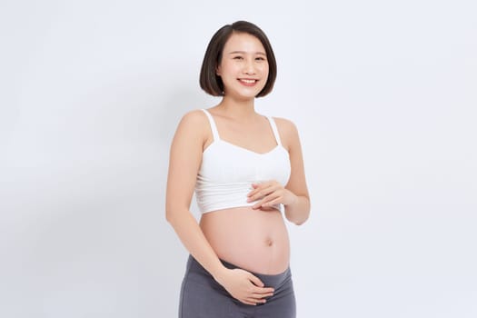 Pregnant woman touching belly looking at camera