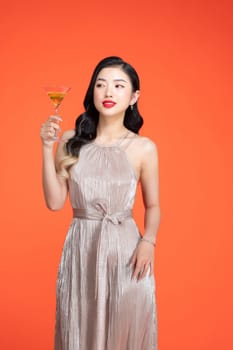 Portrait of attractive young festive asian offering a glass of champagne.