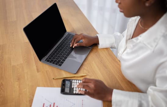 Cropped of black woman using laptop with empty screen, mockup