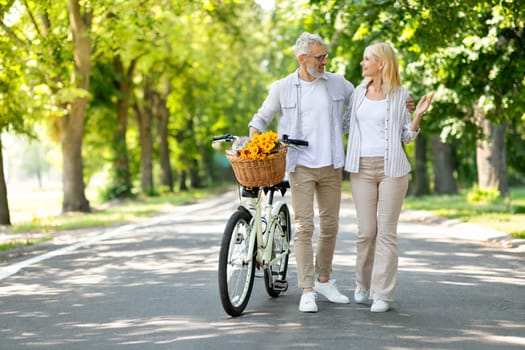 Portrait Of Happy Senior Couple Walking With Retro Bike In City Park