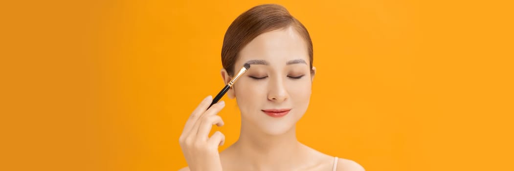 woman applying eyeshadow on eyelid using makeup brush. Web banner.