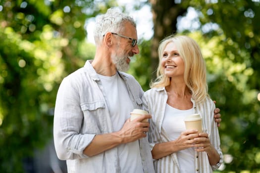 Retirement Leisure. Smiling Senior Spouses Walking Outdoors And Drinking Takeaway Coffee
