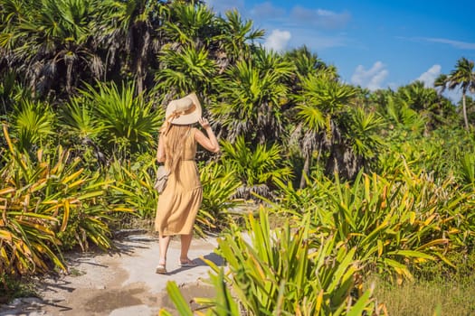 Woman in a hat walks through a tropical park