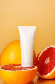 Cosmetic container on background of cut citrus fruit