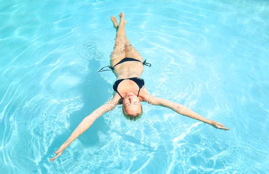 Caucasian lady floating in swimming pool.
