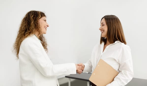 Two Smiling Businesswomen Meeting And Shaking Hands At Modern Office