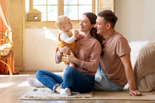 Portrait Of Happy Young Parents Having Fun With Infant Son At Home