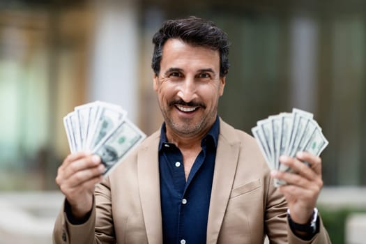 Cash money dollar banknotes in happy middle eastern businessman hand