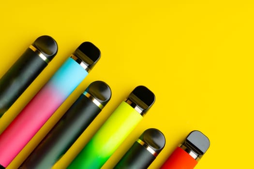 Colorful disposable electronic cigarettes on yellow background