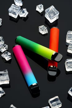 Disposable electronic cigarettes with ice cubes on black background