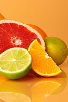 Cut pieces of citrus fruits on orange background