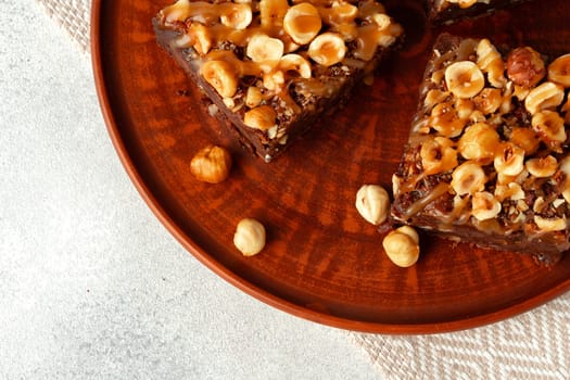 Brownie cake with nuts topping on plate close up
