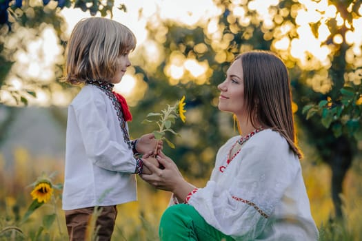 Portrait of beautiful family - 4 years old boy gives sunflower to mother, nature