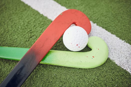 Hockey, stick and ball on green, field or pitch with sports equipment for game, competition or match on ground or floor. Artificial grass, heart or gear on turf for training in sport championship