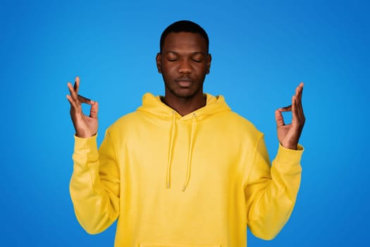 Positive calm young black man with closed eyes meditation, enjoy free time, rest