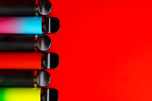 Colorful disposable electronic cigarettes on red background