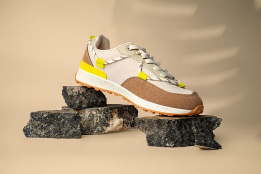 New sneaker shoe on stones on beige studio background