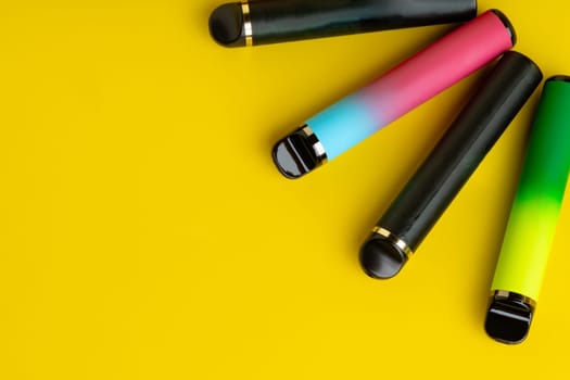 Colorful disposable electronic cigarettes on yellow background