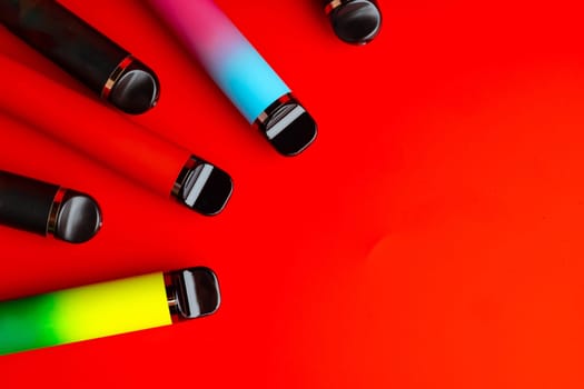 Colorful disposable electronic cigarettes on red background
