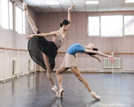 Two Asian ballerinas are dancing in the class.