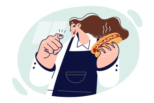 Woman chef of fast food restaurant holding hot dog and pointing finger at screen offering lunch