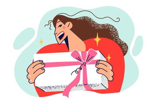 Cheerful woman holds box with gift tied with pink ribbon and laughs rejoicing at receiving prize
