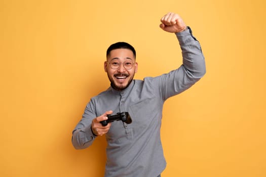 Video Gaming Concept. Euphoric Asian Man With Joystick Celebrating Game Win