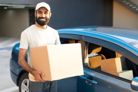 Middle Eastern Deliveryman Holds Cardboard Box Near His Modern Automobile