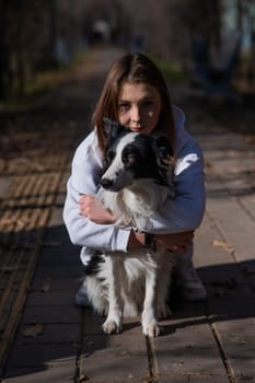 Caucasian woman hugging border collie in autumn park. Portrait of a girl with a dog.