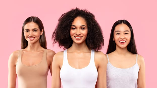 Diversity and natural beauty concept. Young multiracial ladies posing and smiling at camera, pink background, panorama