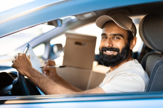 Arabic Deliveryman Notes Delivery Address Sitting With Parcels In Car