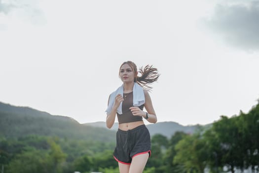 Portrait of young woman running in the city park in the early morning