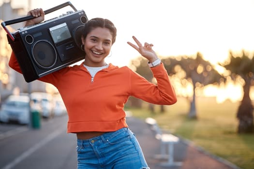 Portrait, peace sign and woman with radio in the street for skating, happiness or fashion. Smile, walking and young girl with a stereo for music and gesture in the road in sunset for urban aesthetic